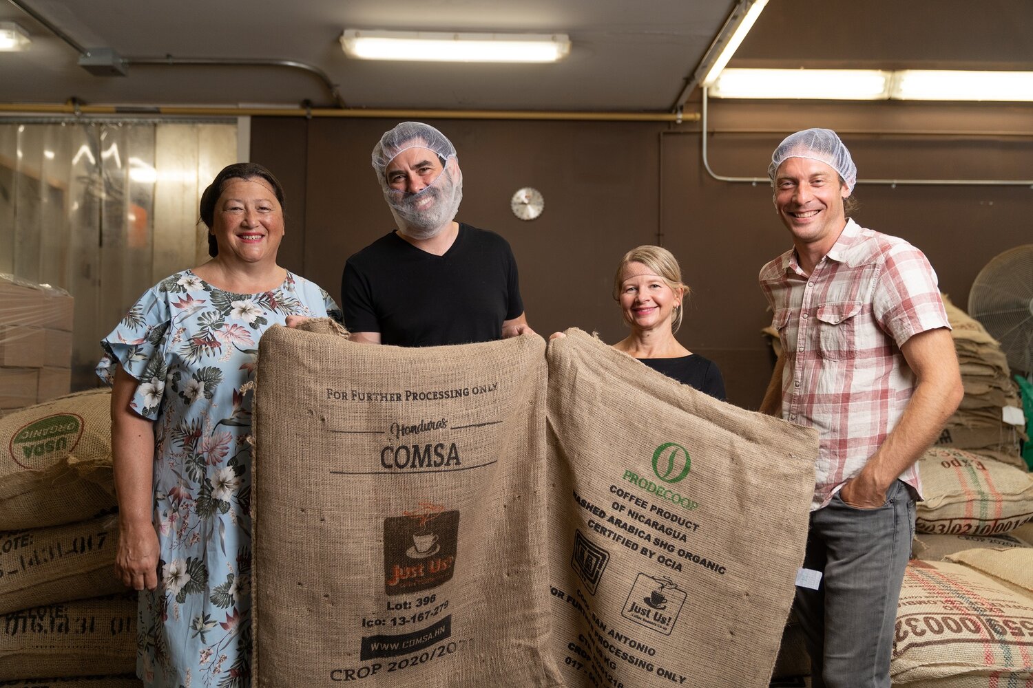Four people hold up coffee sacks