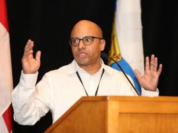 Dr. Harvey Amani Whitfield speaking at a podium.