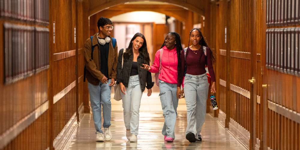 Four students walk and talk together in the Mcnally hallway