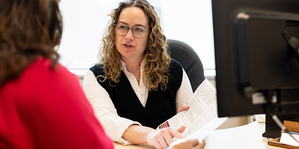 A student advisor shows a student something on a piece of paper.